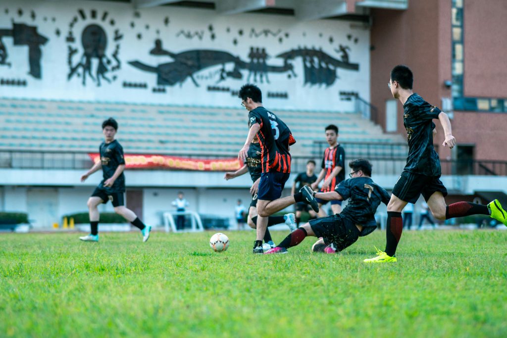 A group of teenagers playing an intense soccer match outdoors on a sunny day.